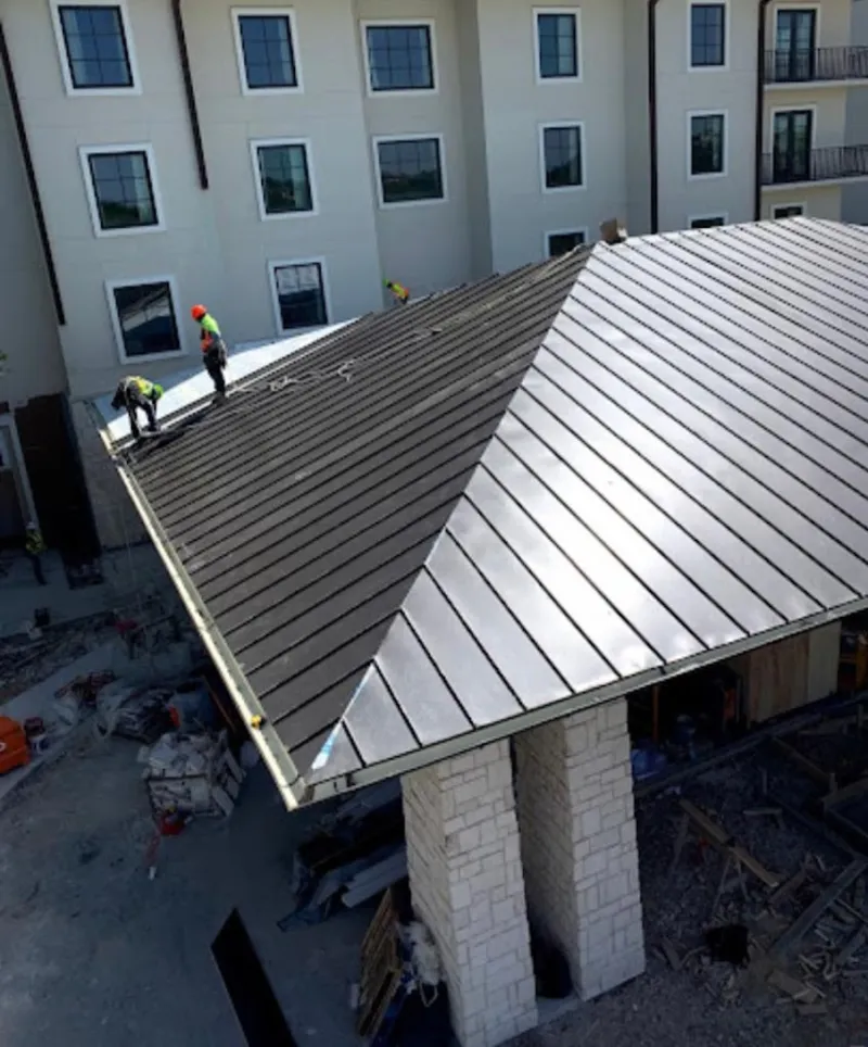 Crew installing standing seam metal roof panels on a commercial project in Orchards